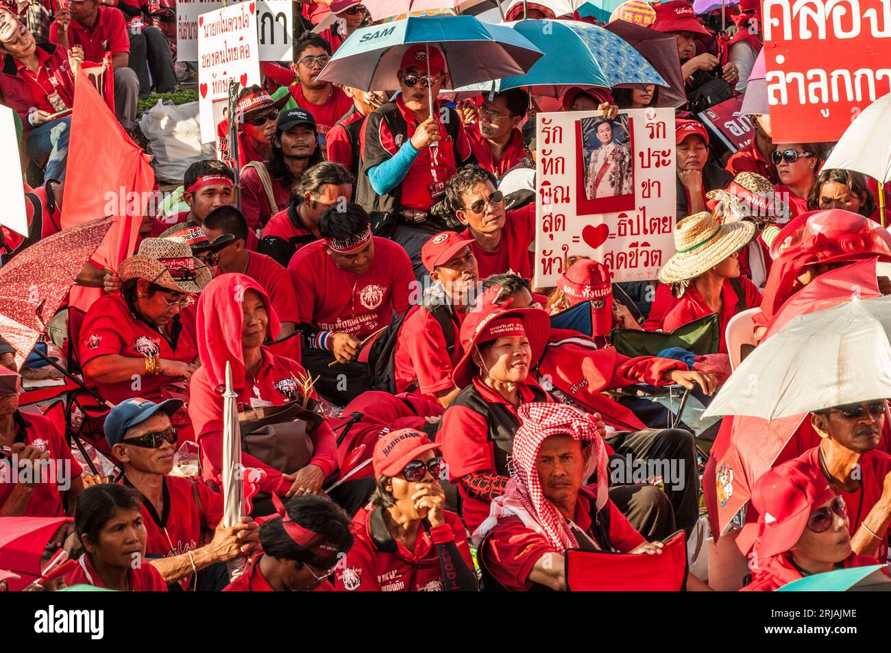 Manifestante con camicia rossa con un cartello con scritto tailandese con foto di Thaksin Shinawatra durante una protesta con camicia rossa. Phan fa Bridge, Bangkok, Thailandia. © Kraig Lieb Foto Stock