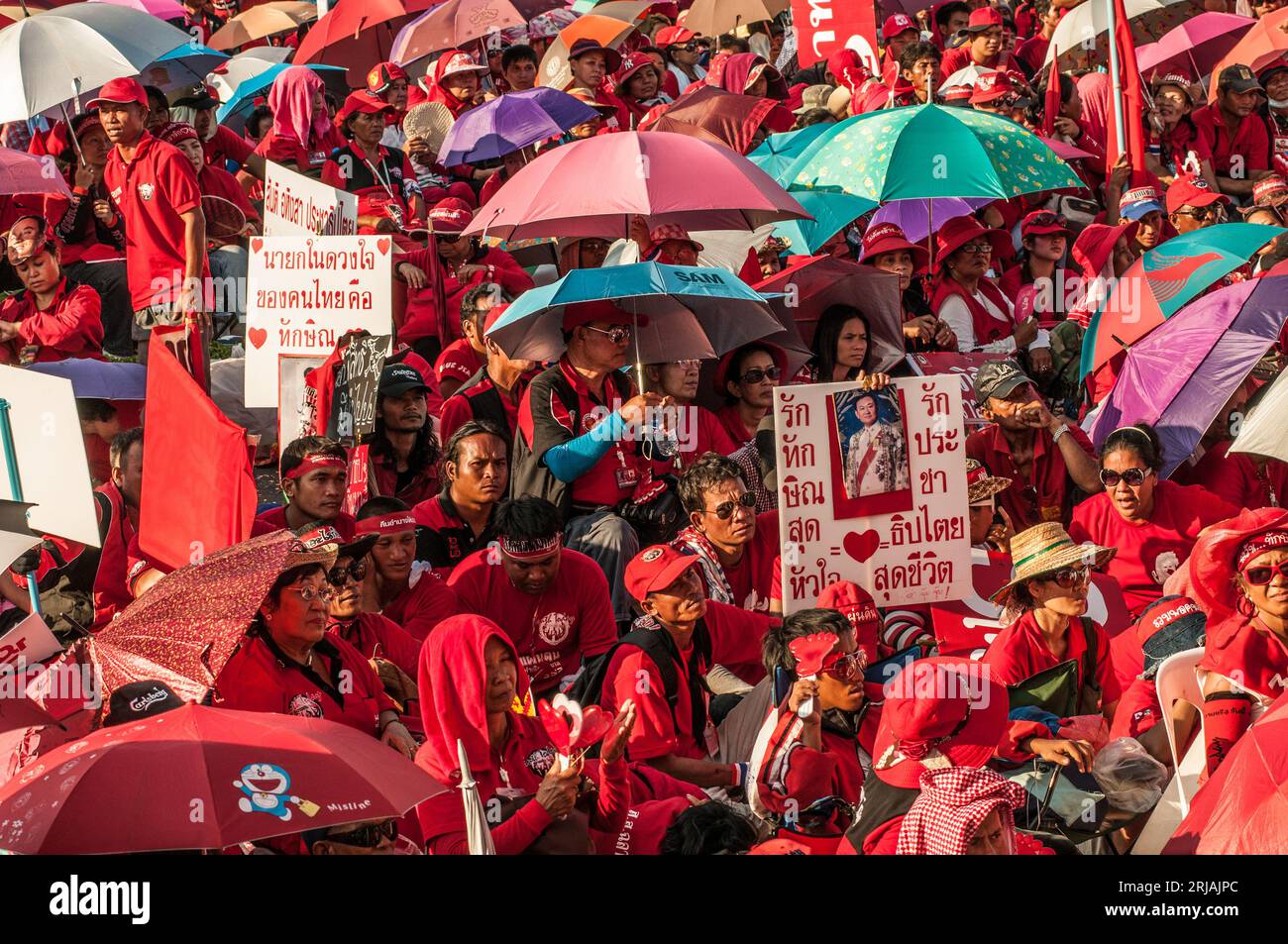 Manifestante con camicia rossa con un cartello con scritto tailandese con foto di Thaksin Shinawatra durante una protesta con camicia rossa. Phan fa Bridge, Bangkok, Thailandia. © Kraig Lieb Foto Stock