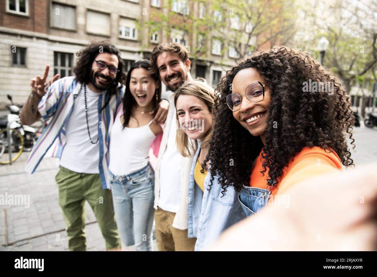 Gruppo multirazziale di amici che ridono e scattano un selfie per strada.allegro gruppo eterogeneo di giovani hipster che scattano una foto all'aperto e guardano Foto Stock