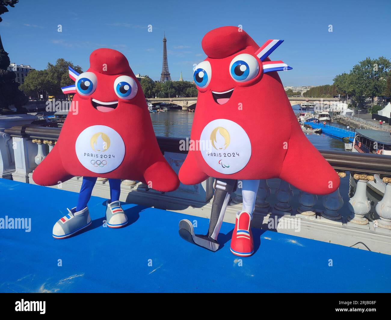Le mascotte olimpiche (L) e paralimpiche (R) Phryges per i giochi di Parigi 2024 sul Pont Alexandre III con la Torre Eiffel sullo sfondo Foto Stock