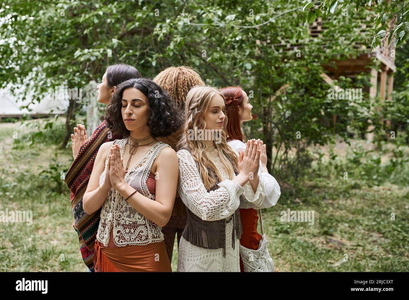 donne multietniche che pregano mentre si mettono da parte all'aperto nel centro di ritiro Foto Stock