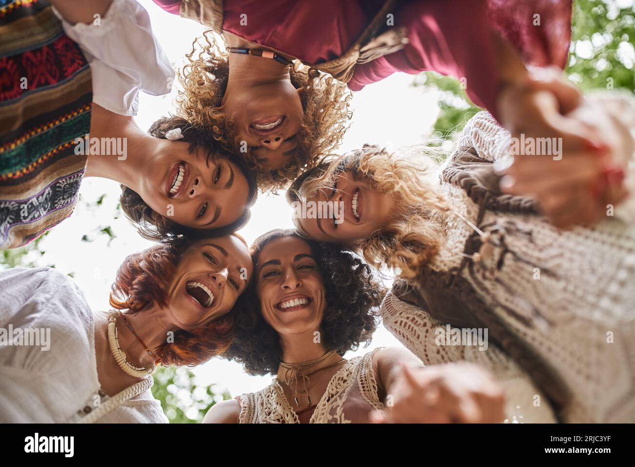 vista dal basso delle eccitanti donne multietniche che guardano la fotocamera all'aperto nel centro di ritiro Foto Stock