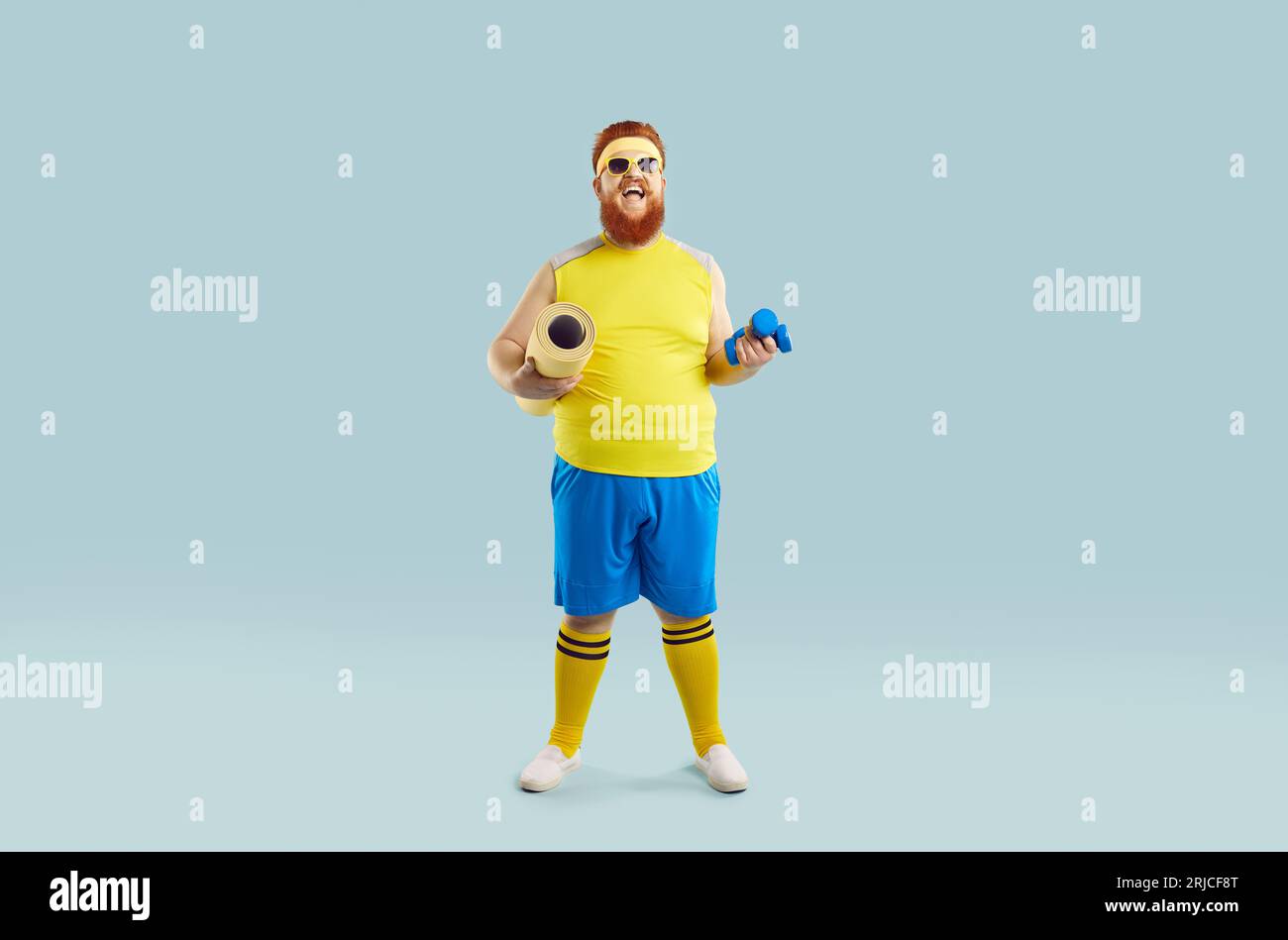 Foto studio di dimensioni normali di un ragazzo grasso divertente con tuta da fitness gialla e blu. Foto Stock