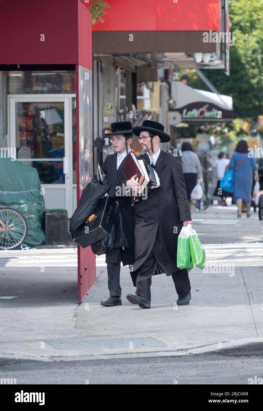 SCENA DI STRADA. Due ebrei chassidici vestiti in modo simile girano un angolo di Lee Avenue a Williamsburg, Brooklyn, New York. Foto Stock