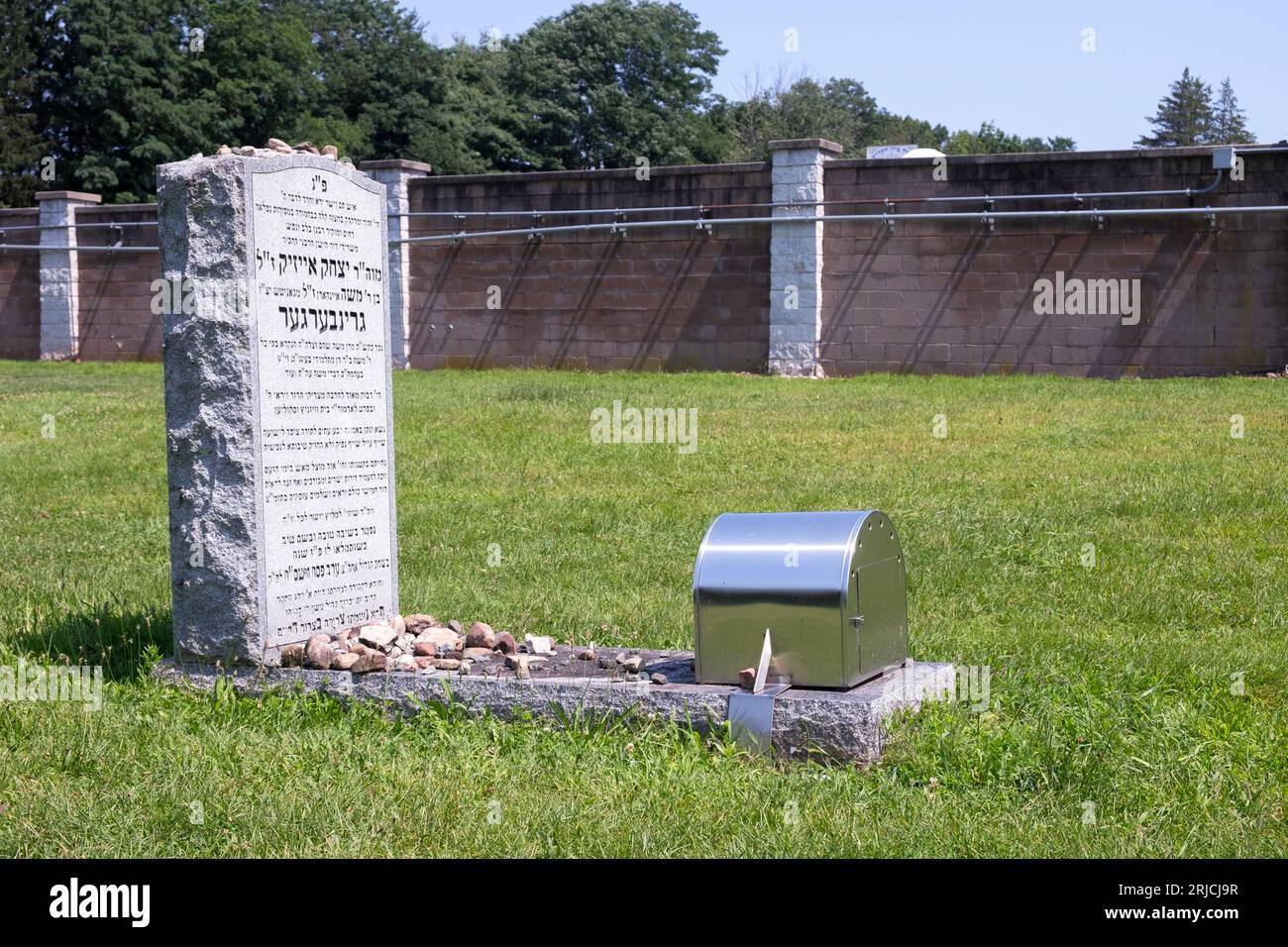 Una tomba ebraica, una lapide e un involucro per le candele al cimitero di Viznits a Monsey NY. La lapide è ricoperta di piccole pietre, come è tradizione. Foto Stock