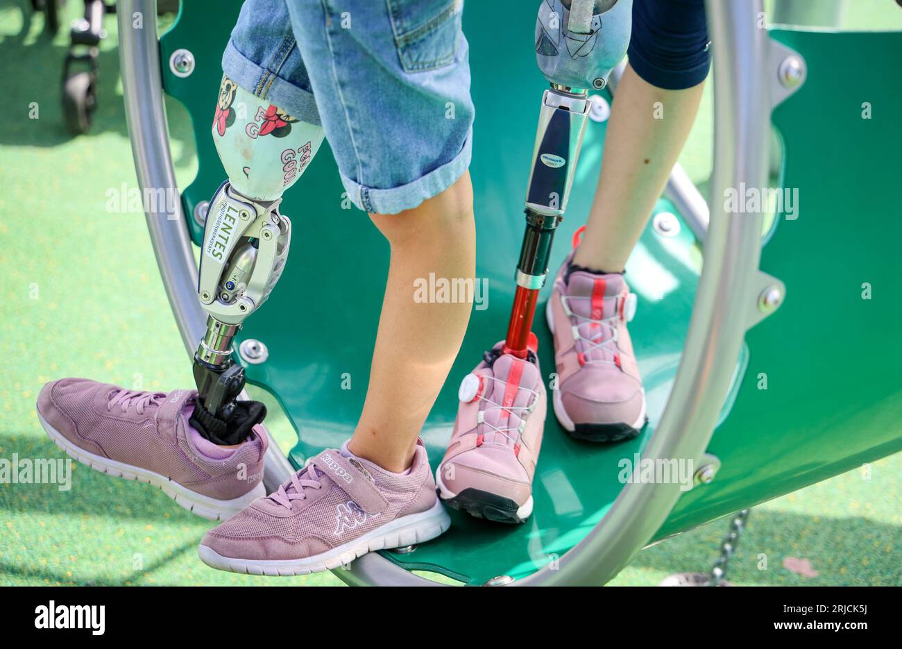 Brema, Germania. 22 agosto 2023. Le ragazze con le gambe protesiche si trovano su un'attrezzatura da gioco all'apertura del primo parco giochi inclusivo a Brema, presso il centro diurno della congregazione della chiesa di Dietrich Bonhoeffer. Il parco giochi offre anche accesso senza barriere a varie attrezzature per i bambini con disabilità. Crediti: Focke Strangmann/dpa/Alamy Live News Foto Stock