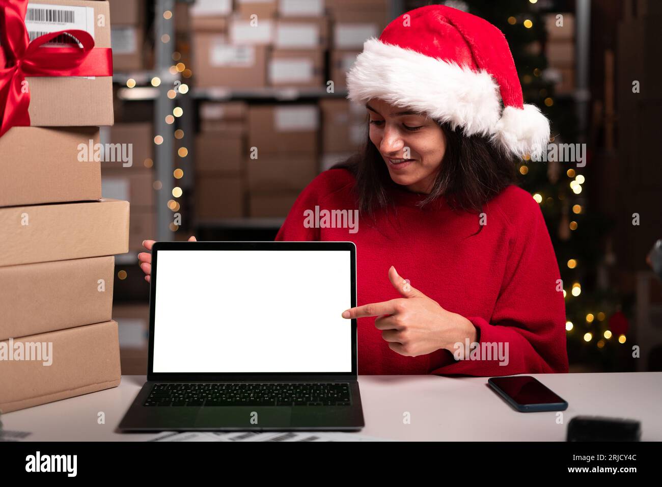 Responsabile del magazzino che utilizza un computer portatile con spazio vuoto per il mock-up e punta il dito su di esso, saldi natalizi, spazio per la pubblicità Foto Stock