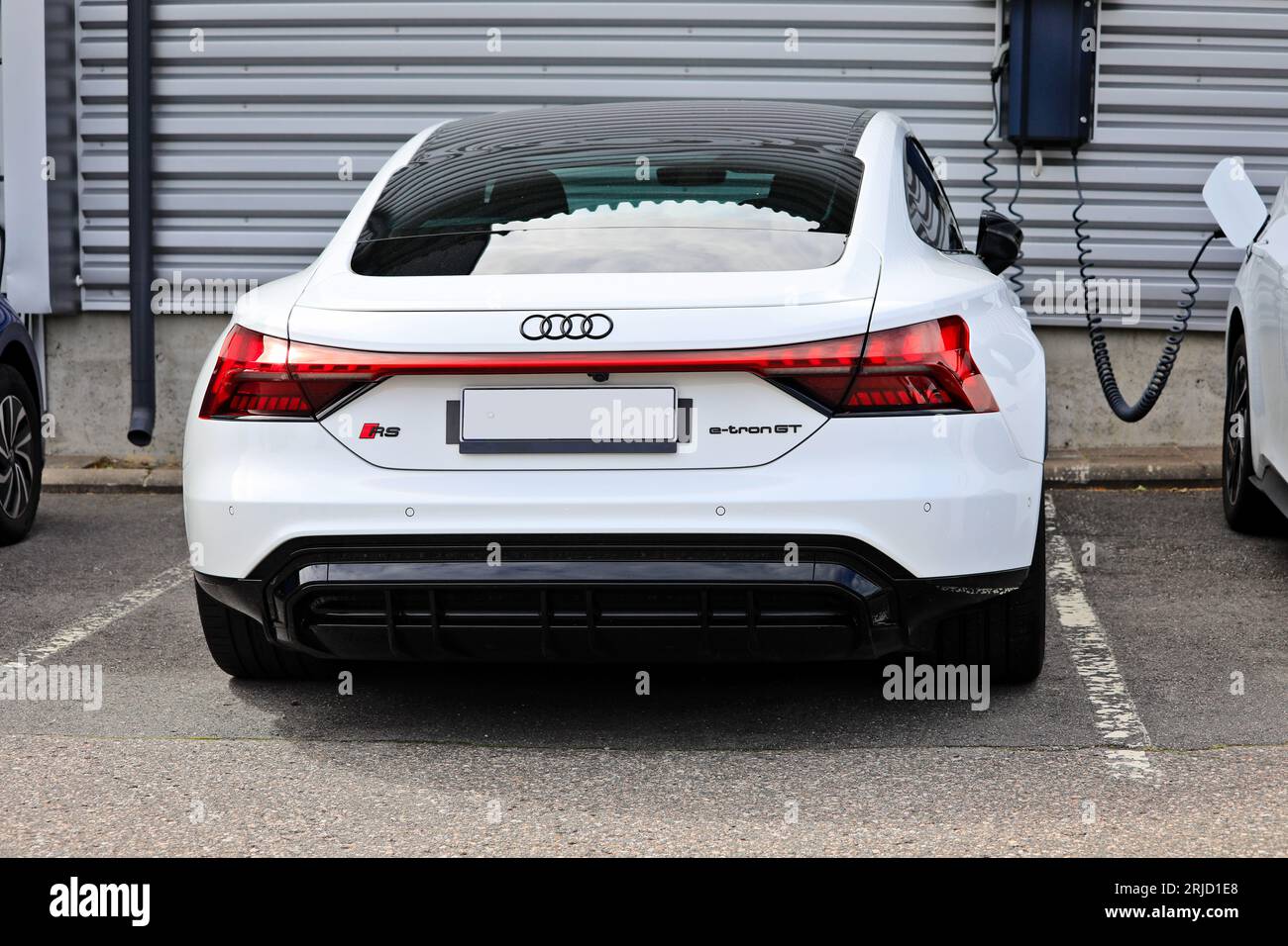 Auto elettrica Audi e-tron GT RS F83 bianca parcheggiata vicino a un caricatore da parete di un concessionario, vista posteriore. Salo, Finlandia. 13 agosto 2023. Foto Stock