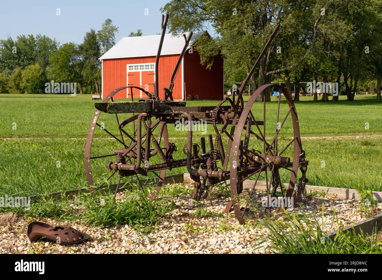 Vecchio fienile rosso e vecchie attrezzature agricole arrugginite nell'Illinois rurale. Foto Stock