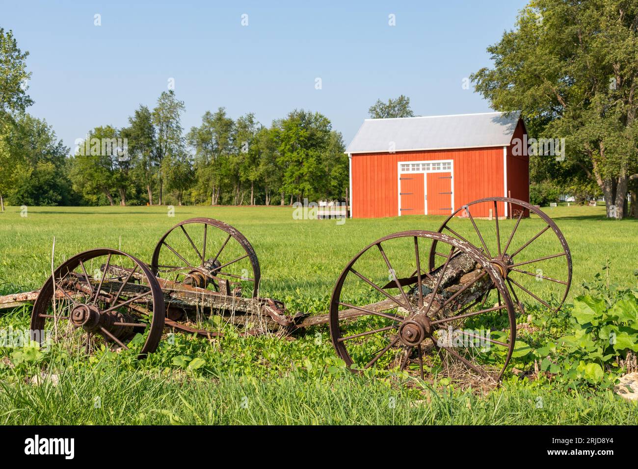 Vecchio fienile rosso e vecchie attrezzature agricole arrugginite nell'Illinois rurale. Foto Stock