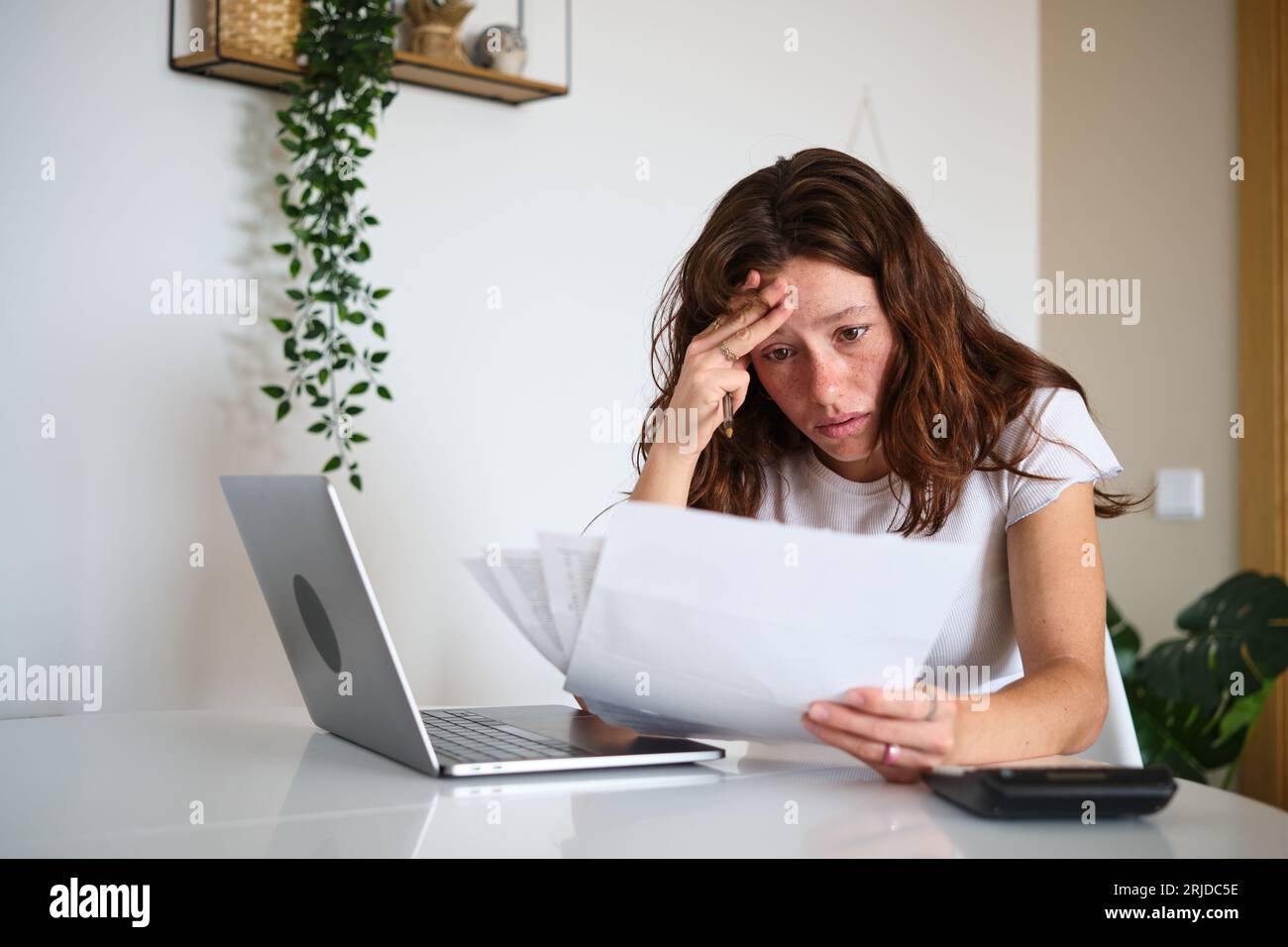 Donna preoccupata che legge bollette problematiche a casa Foto Stock