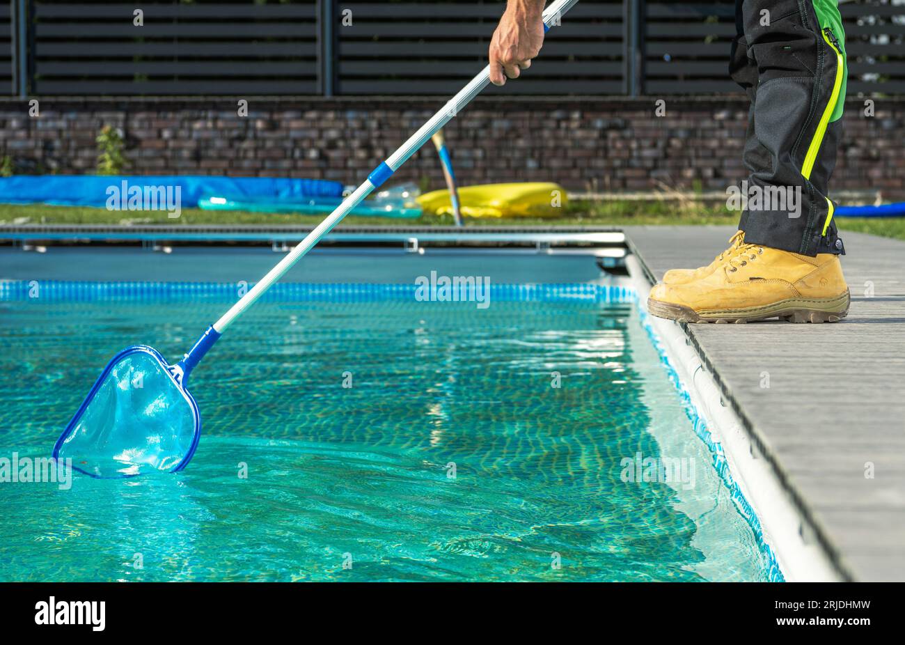 Lavoratore in piscina professionale caucasico con una rete per la pulizia della piscina piscina piscina all'aperto residenziale Foto Stock
