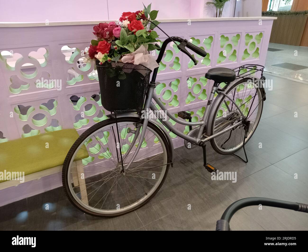 una bicicletta vecchio stile con fiori sul cestino Foto Stock