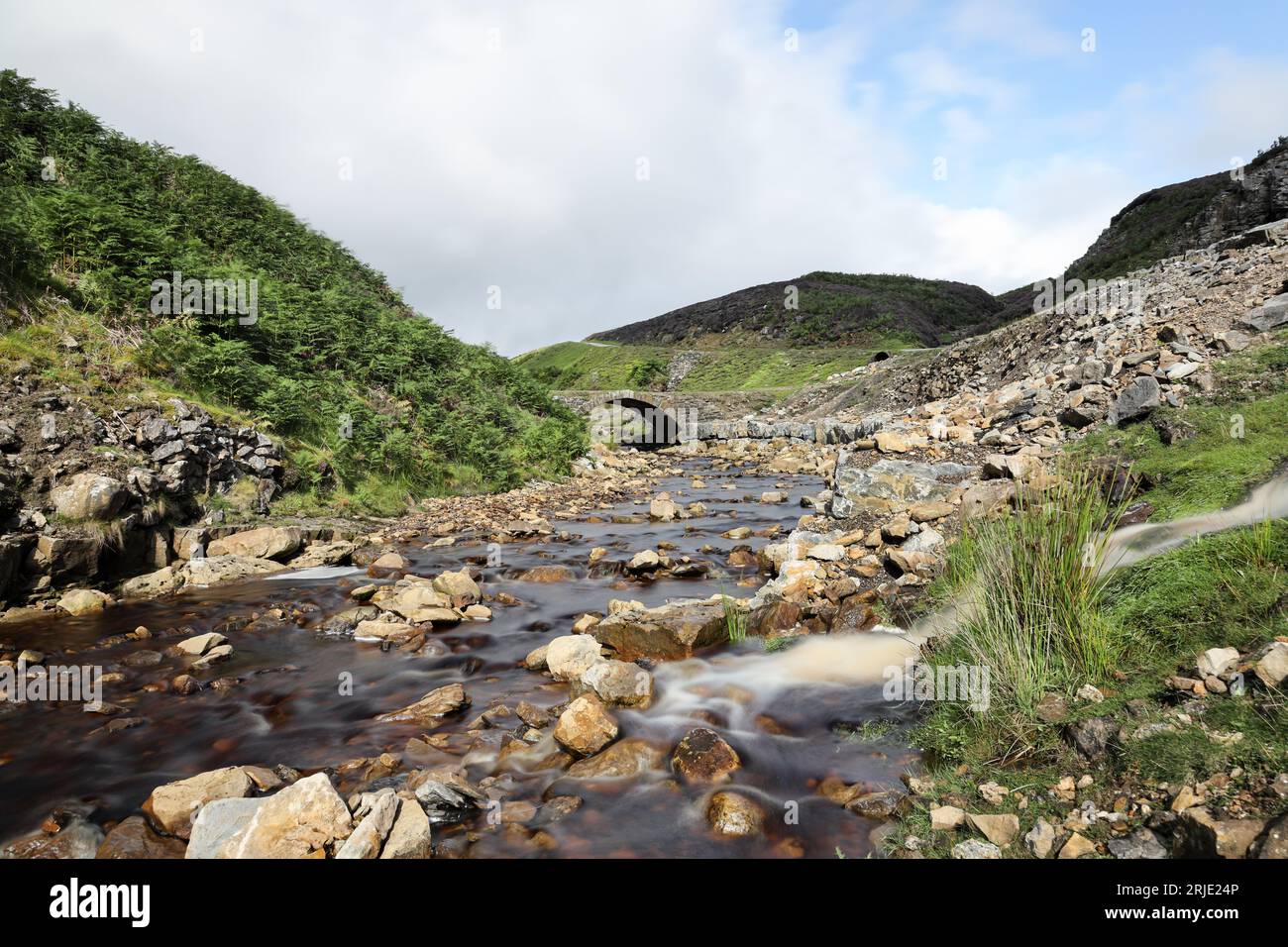 Old Gang Beck, (noto anche come Mill Gill) e ponte nel paesaggio post-industriale che circonda l'Old Gang Smelting Mill, Swaledale, Yorkshire Dale Foto Stock