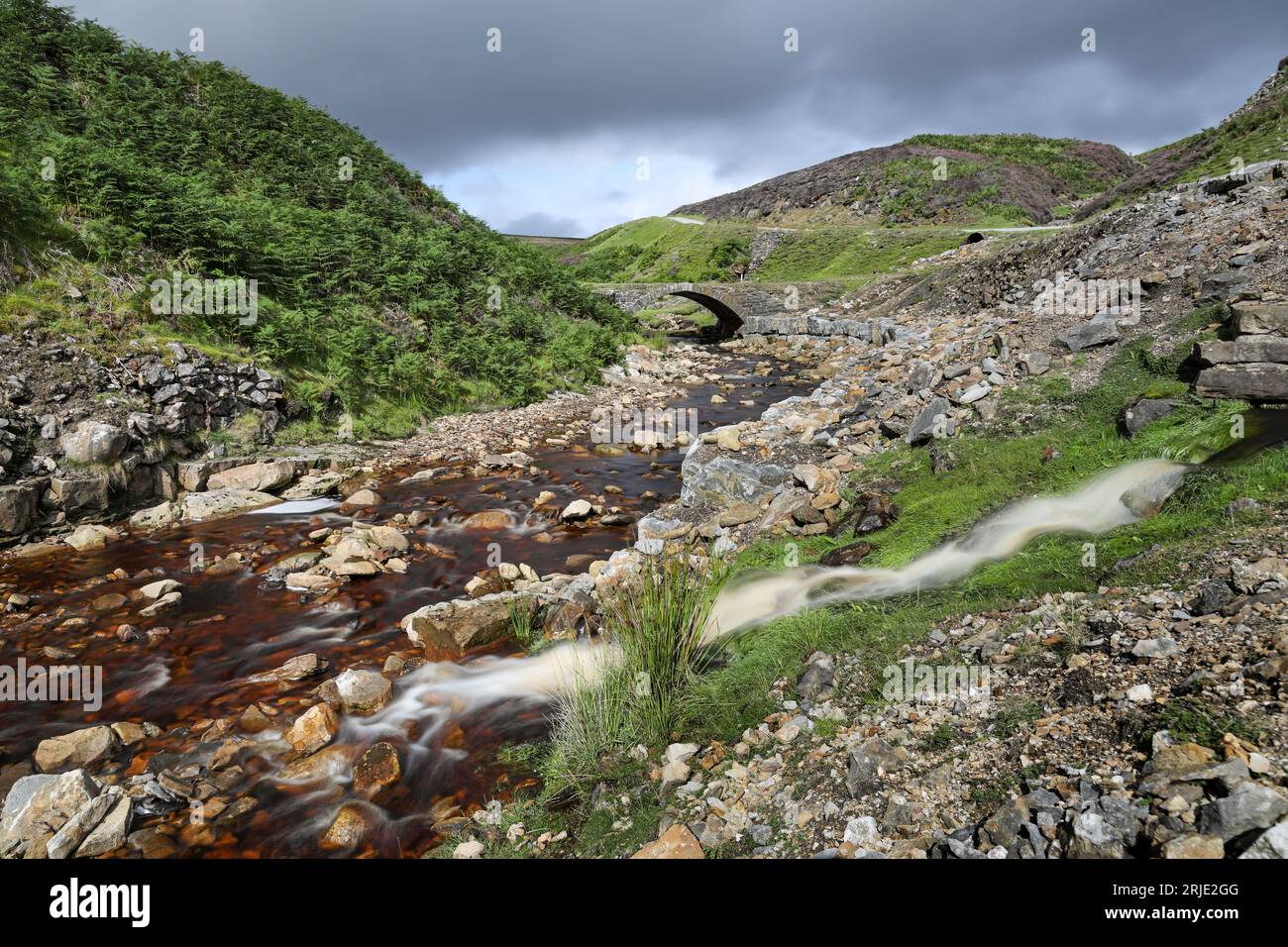 Old Gang Beck, (noto anche come Mill Gill) e ponte nel paesaggio post-industriale che circonda l'Old Gang Smelting Mill, che sta lentamente diventando recl Foto Stock