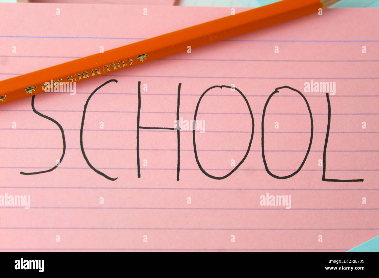 Una foto della parola "Scuola" scritta su una scheda rosa con sopra una matita. Foto Stock