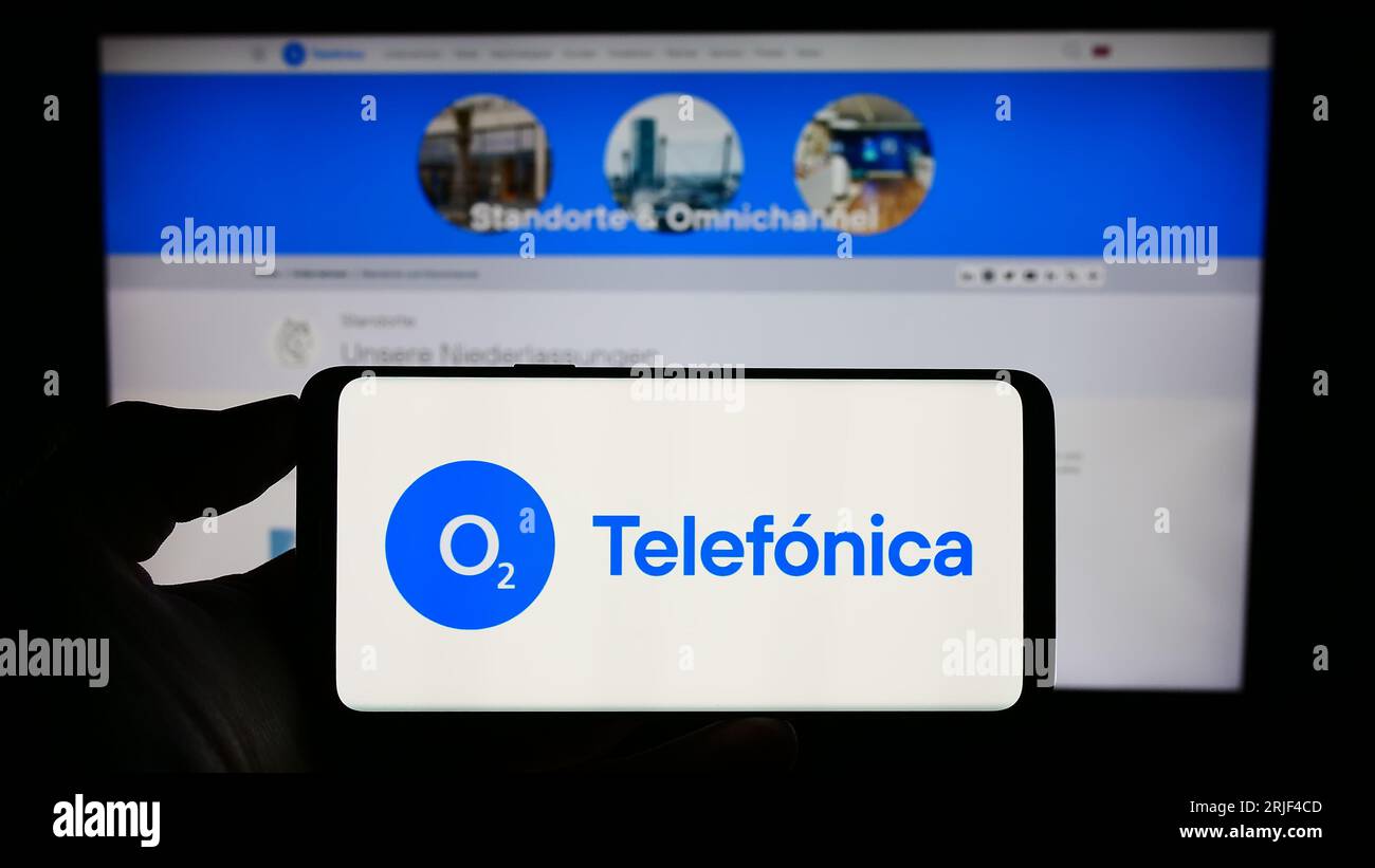 Persona che possiede uno smartphone con il logo della società telefonica Deutschland Holding AG sullo schermo davanti al sito Web. Concentrarsi sul display del telefono. Foto Stock
