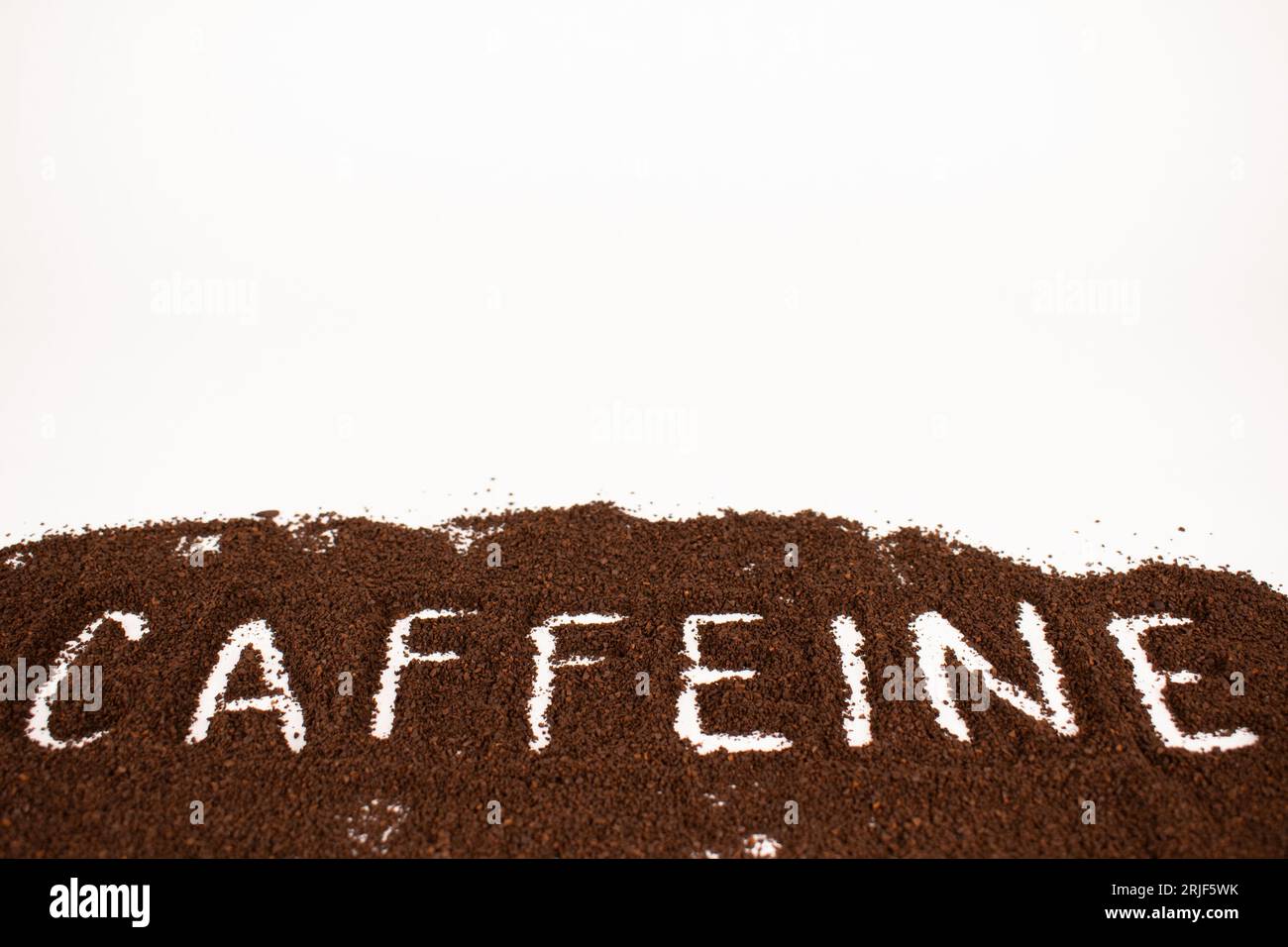 Caffeina scritta in un mucchio di fondi di caffè arrosto scuro Foto Stock