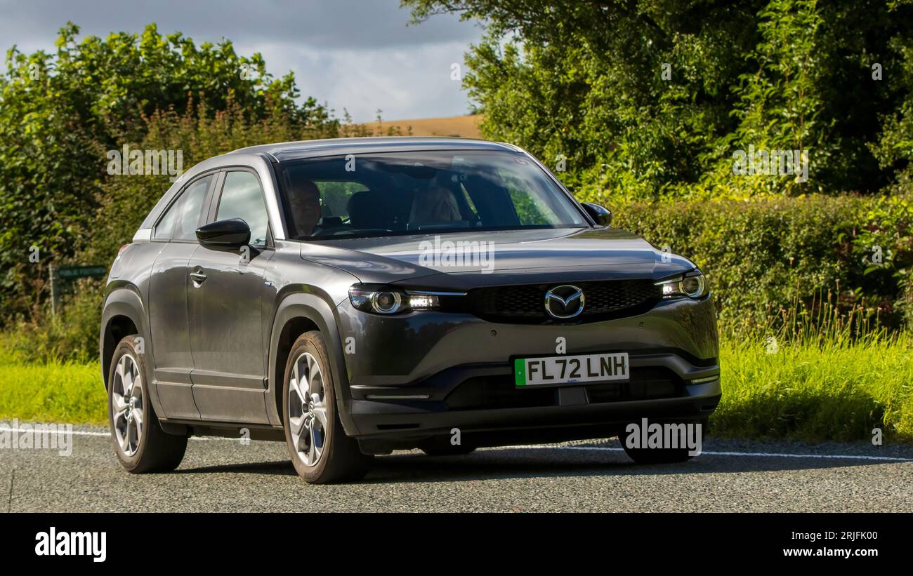 Woburn,Beds.UK - 19 agosto 2023: 2022 Mazda MX-30 auto elettrica che viaggia su una strada di campagna inglese. Foto Stock