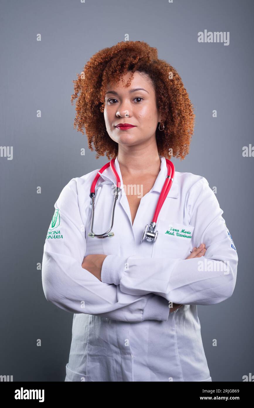 Giovane graziosa studentessa di medicina veterinaria dai capelli rossi in posa per una foto in camice bianco. Concetto di cura degli animali. Foto Stock