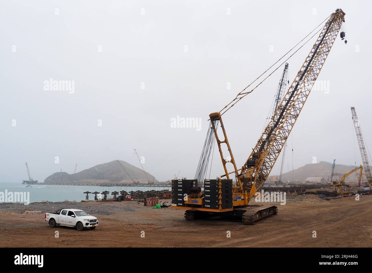 Grandi gru che lavorano presso le strutture portuali di Chancay, ancora in costruzione sulla costa peruviana, 60 km a nord di Lima. Il porto di Chancay sarebbe il fulcro del Pacifico sudamericano, con capacità di ricevere tre navi e in grado di caricare tra 18.000 e 24.000 container, motivo per cui è considerato la porta del commercio marittimo diretto dal Sud America all'Asia e all'Oceania. Il porto è stato costruito dalla Cosco Shipping dalla Cina Foto Stock