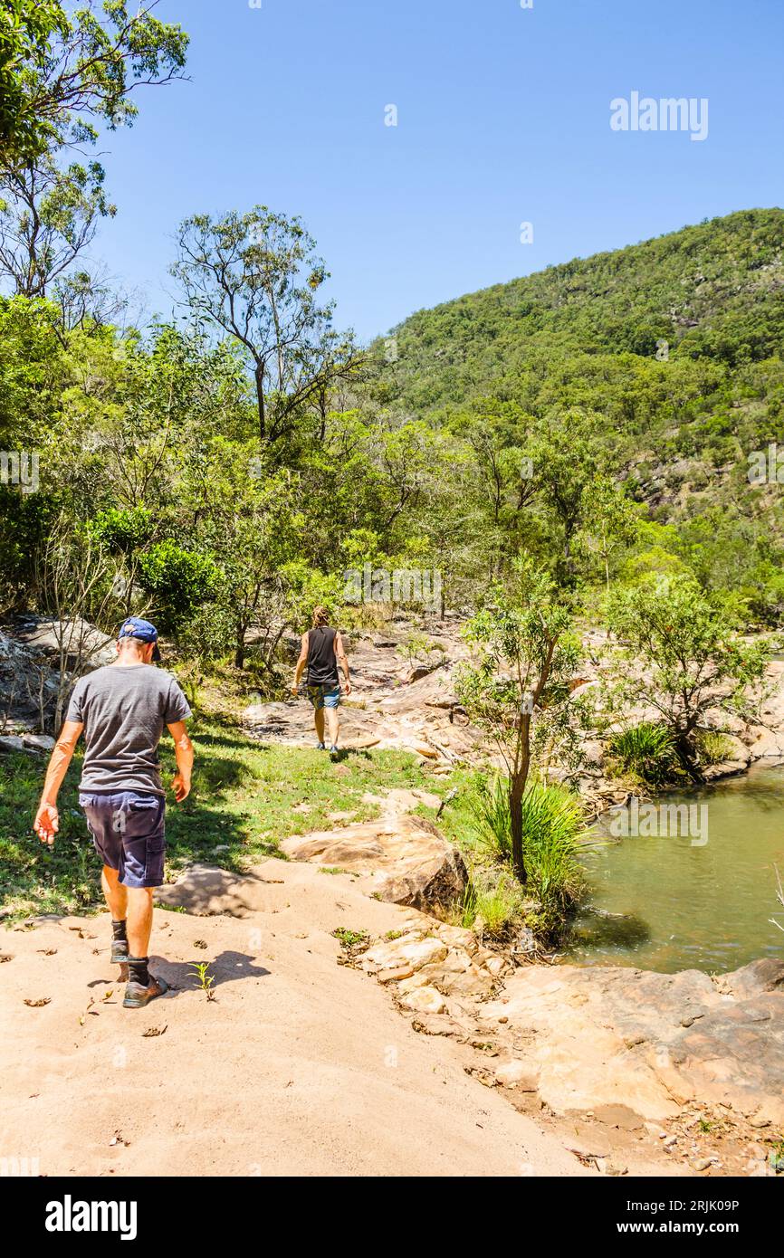 Gli esploratori dell'Outback seguono un percorso panoramico attraverso la natura selvaggia verde con ruscelli e rive rocciose del fiume. Mount Perry, Queensland, Australia Foto Stock