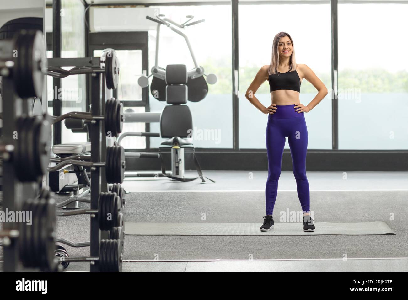 Ritratto a figura intera di una giovane bionda con leggings e top sportivo corto in palestra Foto Stock