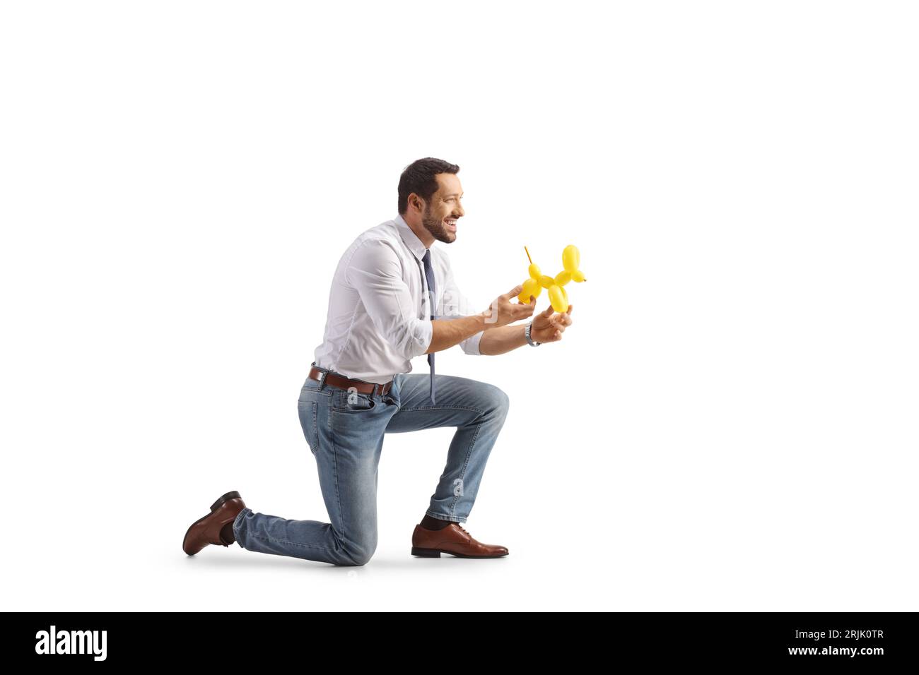 Foto del profilo di un uomo inginocchiato e che tiene in mano un cane fatto da un palloncino isolato su sfondo bianco Foto Stock