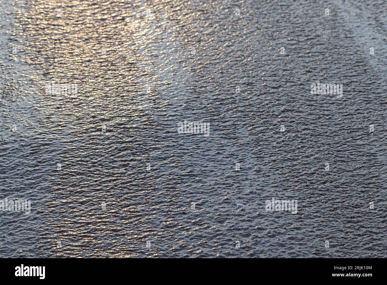 Superficie dell'acqua costiera con ondulazione sulla sabbia, texture naturale astratta dello sfondo Foto Stock