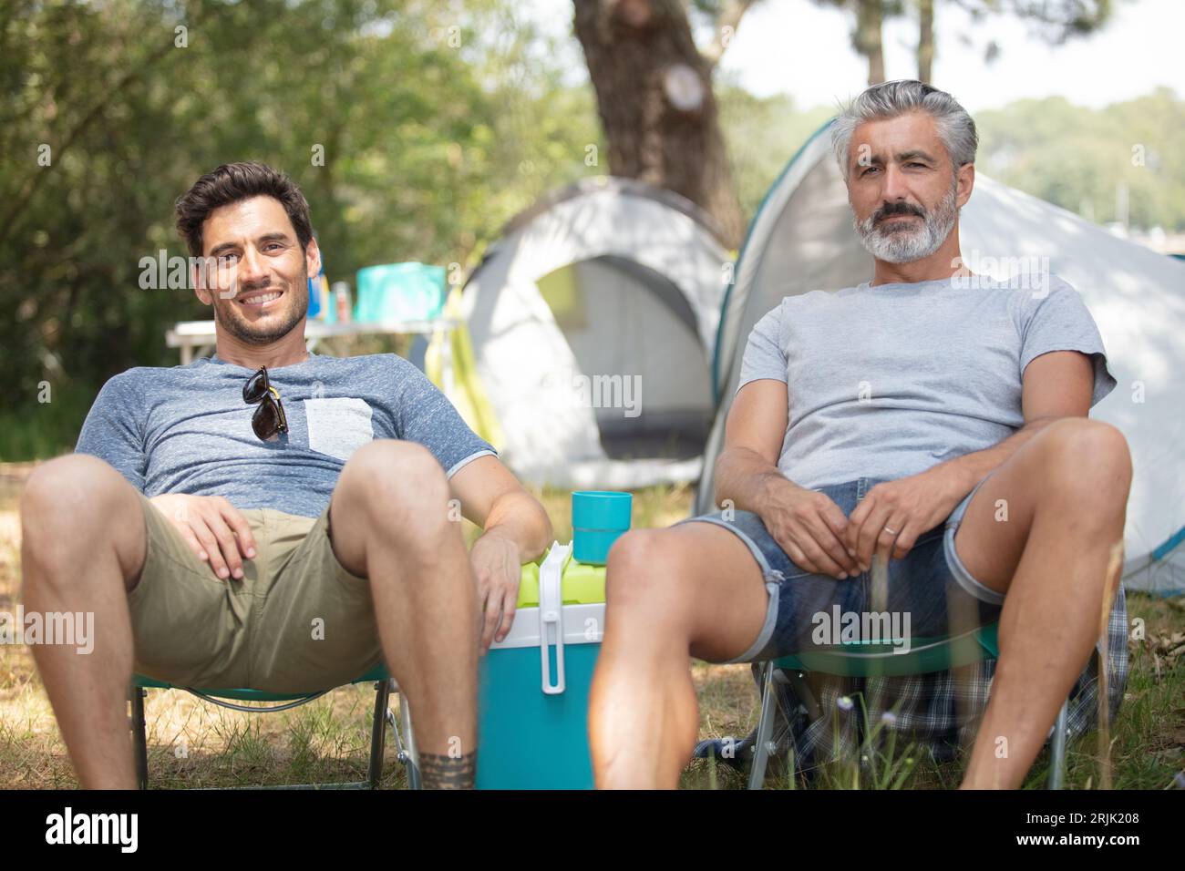 due uomini che si rilassano vicino alle tende Foto Stock