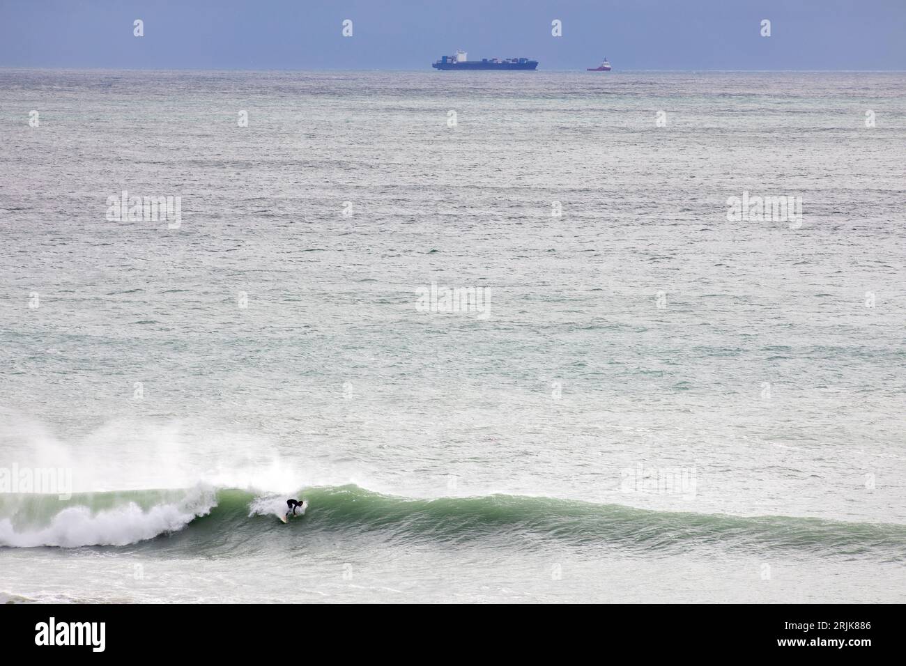Foto di Tim Cuff - 20 maggio 2023 - Un surfista sfrutta al massimo il grande gonfiore di Cable Bay. Il maltempo ha portato in vista la nave rotta Shiling f Foto Stock