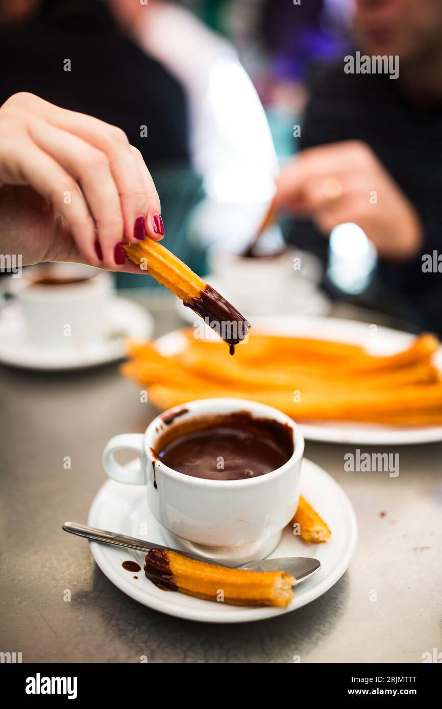 Mangiare Churros a Madrid, Spagna, immersi in cioccolato, specialità gastronomiche, cucina, esperienza culinaria raffinata, cultura, cibo locale Foto Stock