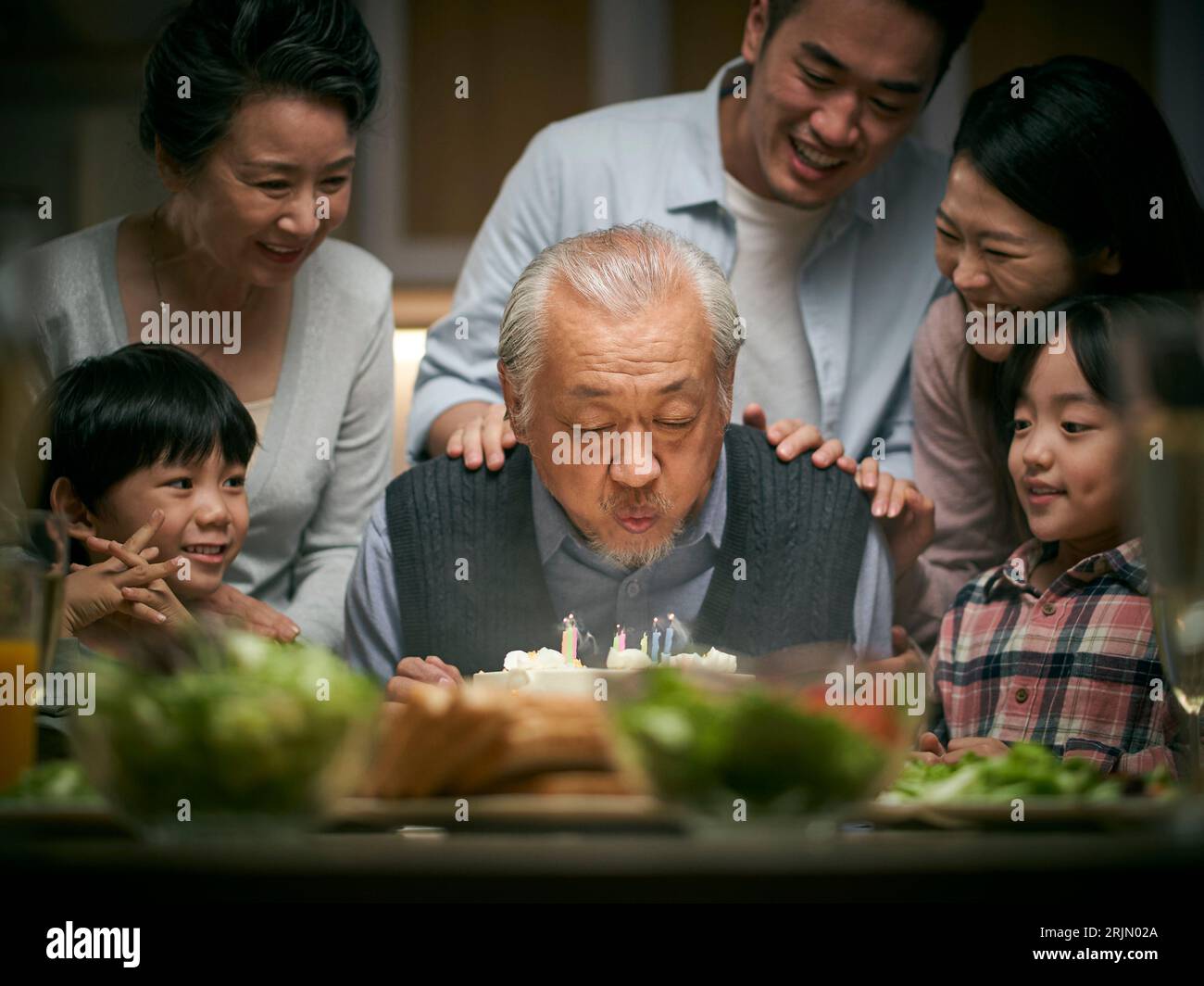 felice famiglia asiatica di tre generazioni che festeggia il compleanno del nonno a casa Foto Stock