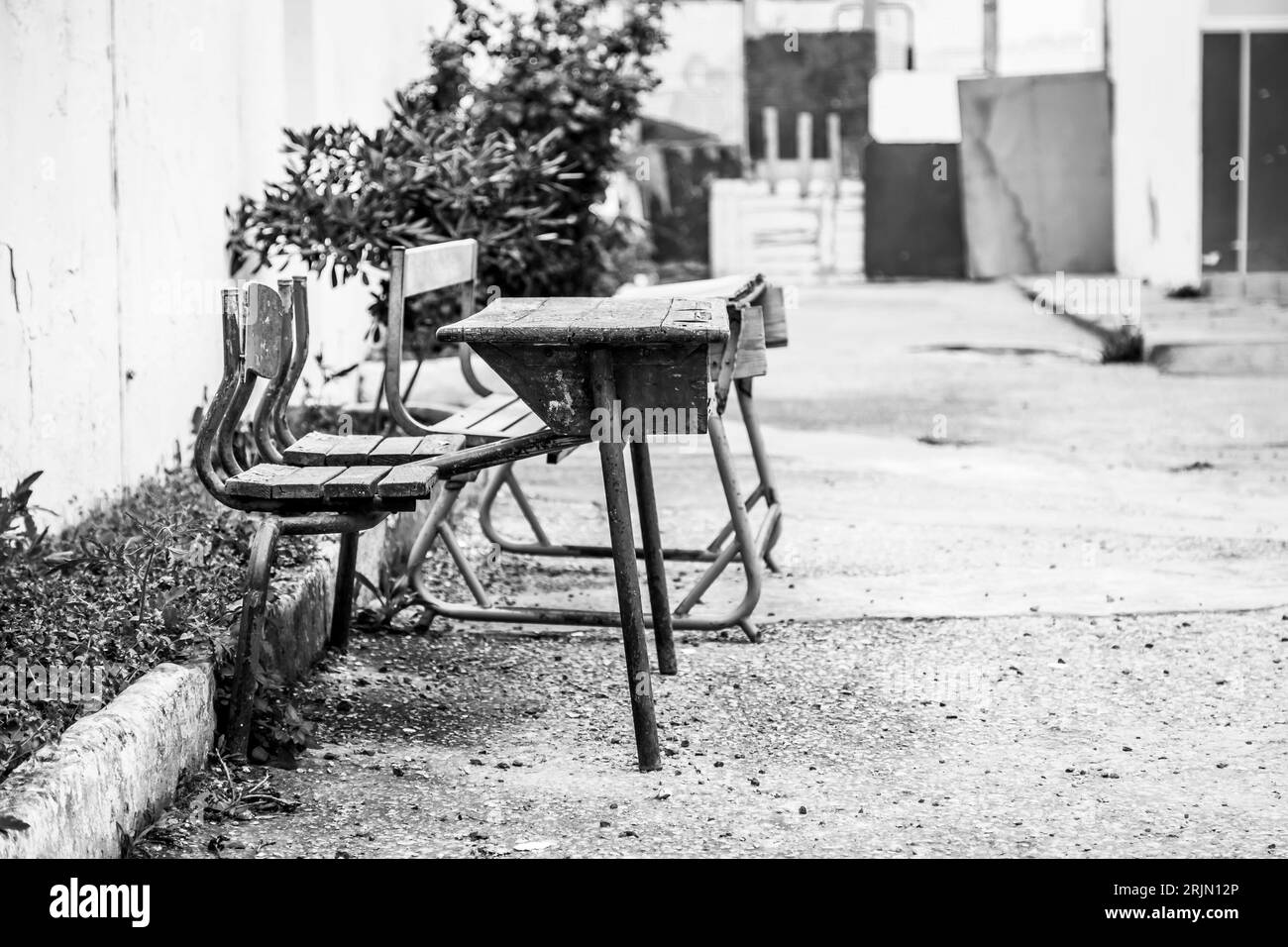 Questa immagine cattura tavoli di legno situati di fronte ad un edificio in mattoni nel vivace paesaggio cittadino della Tunisia Foto Stock