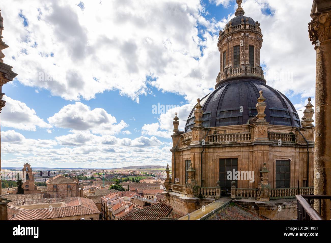Campanile in stile barocco e cupola dell'edificio la Clerecía a Salamanca, Spagna, con facciata decorativa scolpita, paesaggio urbano di Salamanca sullo sfondo. Foto Stock