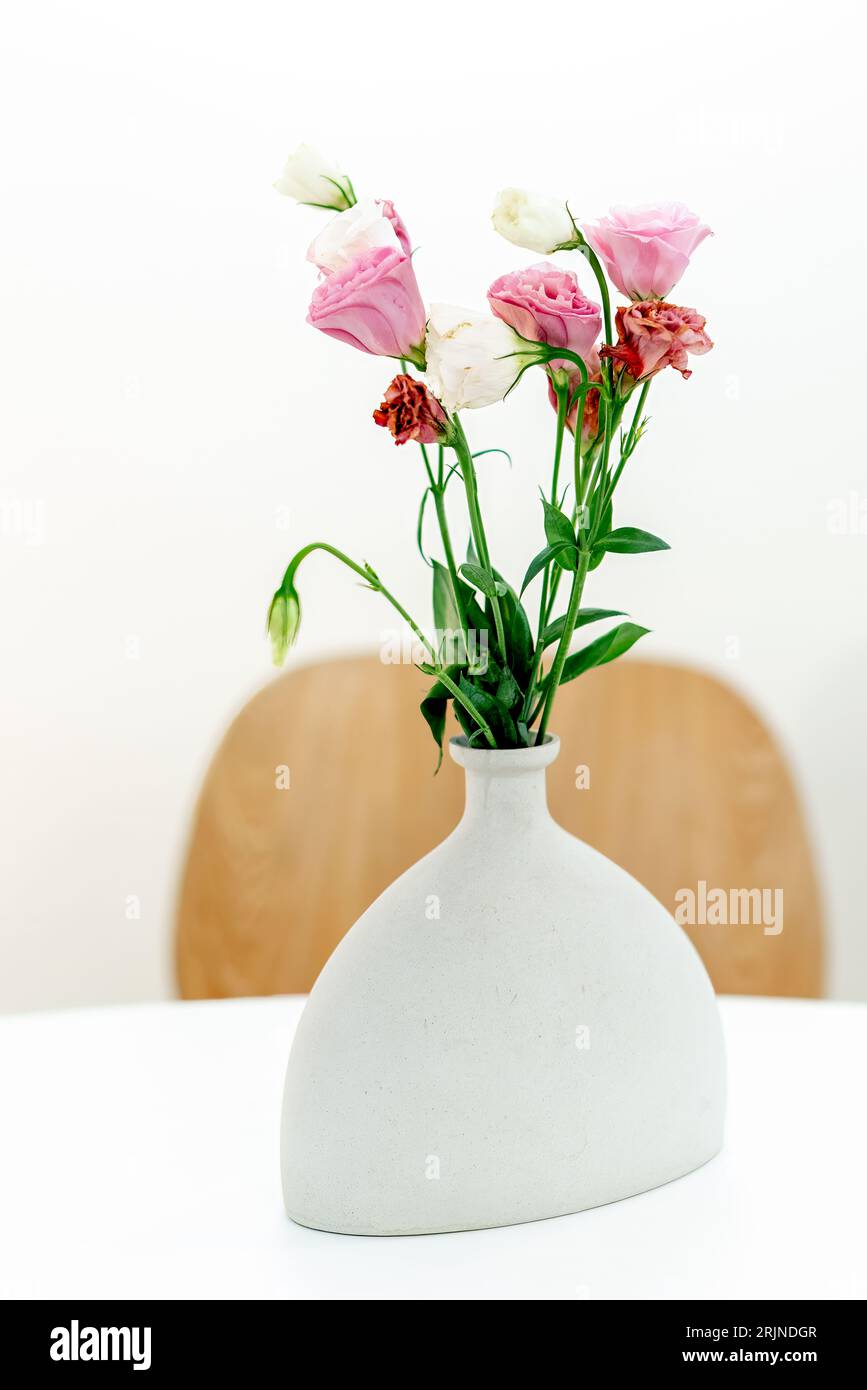 Un elegante vaso in ceramica bianca pieno di un vivace bouquet di fiori multicolori Foto Stock