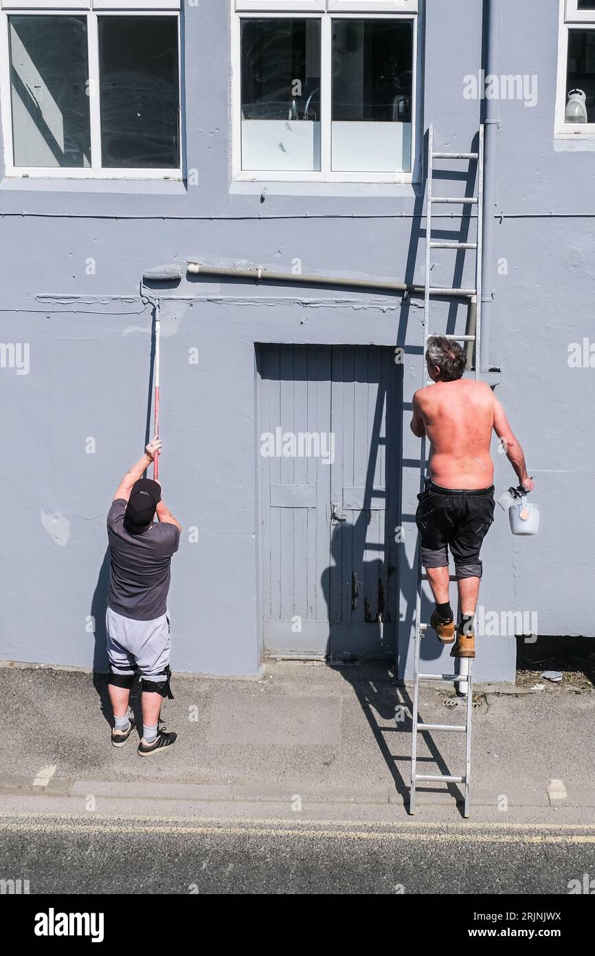 Due uomini dipingono l'esterno di un edificio a Newquay in Cornovaglia, nel Regno Unito. Foto Stock