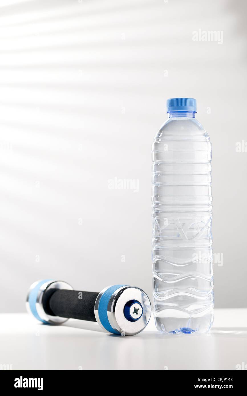 Manubri e acqua in bottiglia, acqua potabile dopo l'allenamento per una maggiore freschezza. Foto Stock
