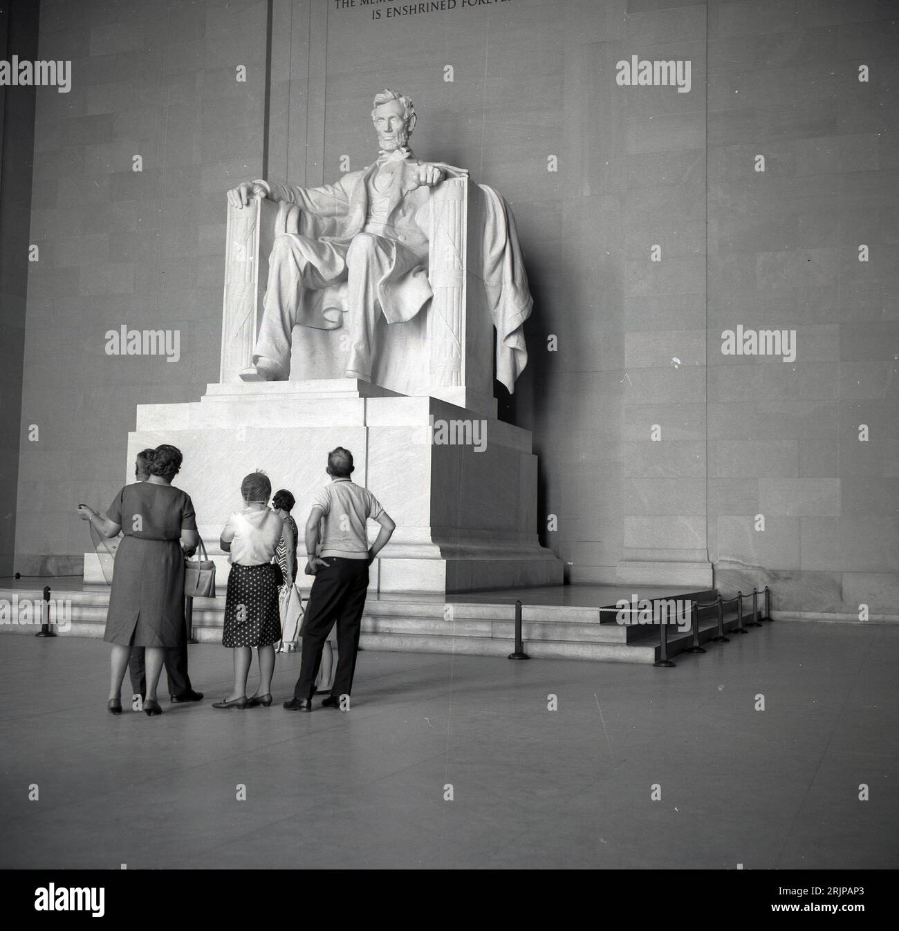 Anni '1960, storica, una famiglia che guarda la statua di Arabham Lincoln all'interno del Lincoln Memorial sulla National mail, Washington DC, USA. Progettata da Daniel Chester French, la grande statua in marmo del XVI presidente fu completata nel 1920, con una presentazione formale nel 1922. Foto Stock