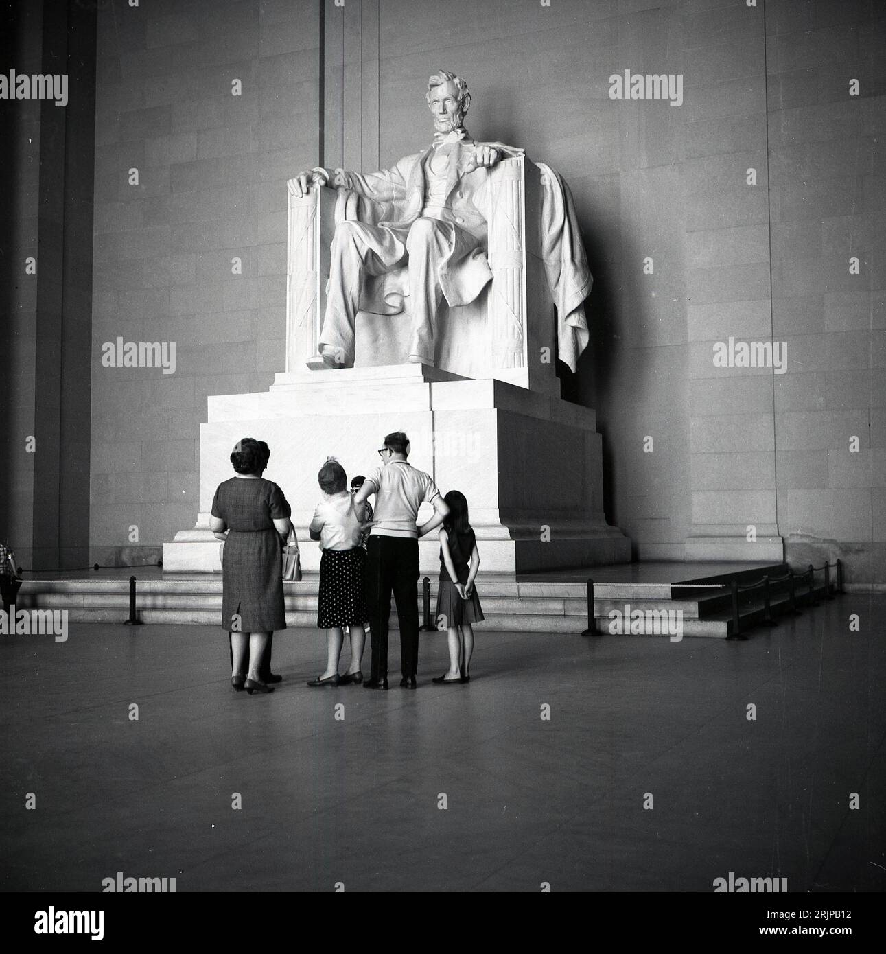 Anni '1960, storica, una famiglia che guarda la statua di Arabham Lincoln all'interno del Lincoln Memorial sulla National mail, Washington DC, USA. Progettata da Daniel Chester French, la grande statua in marmo del XVI presidente fu completata nel 1920, con una presentazione formale nel 1922. Foto Stock