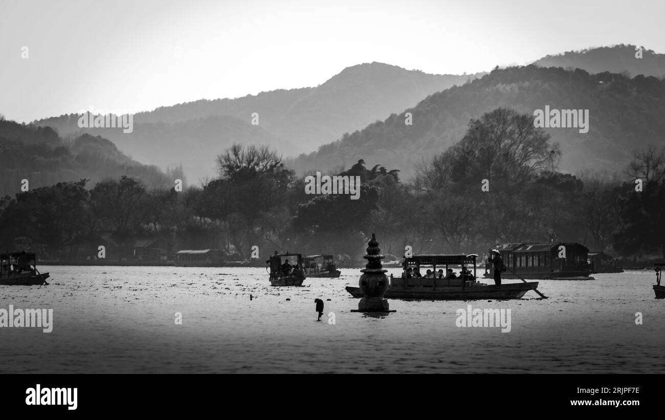 Un paesaggio panoramico caratterizzato da un corpo d'acqua con diverse piccole barche che galleggiano nella nebbiosa luce del mattino Foto Stock