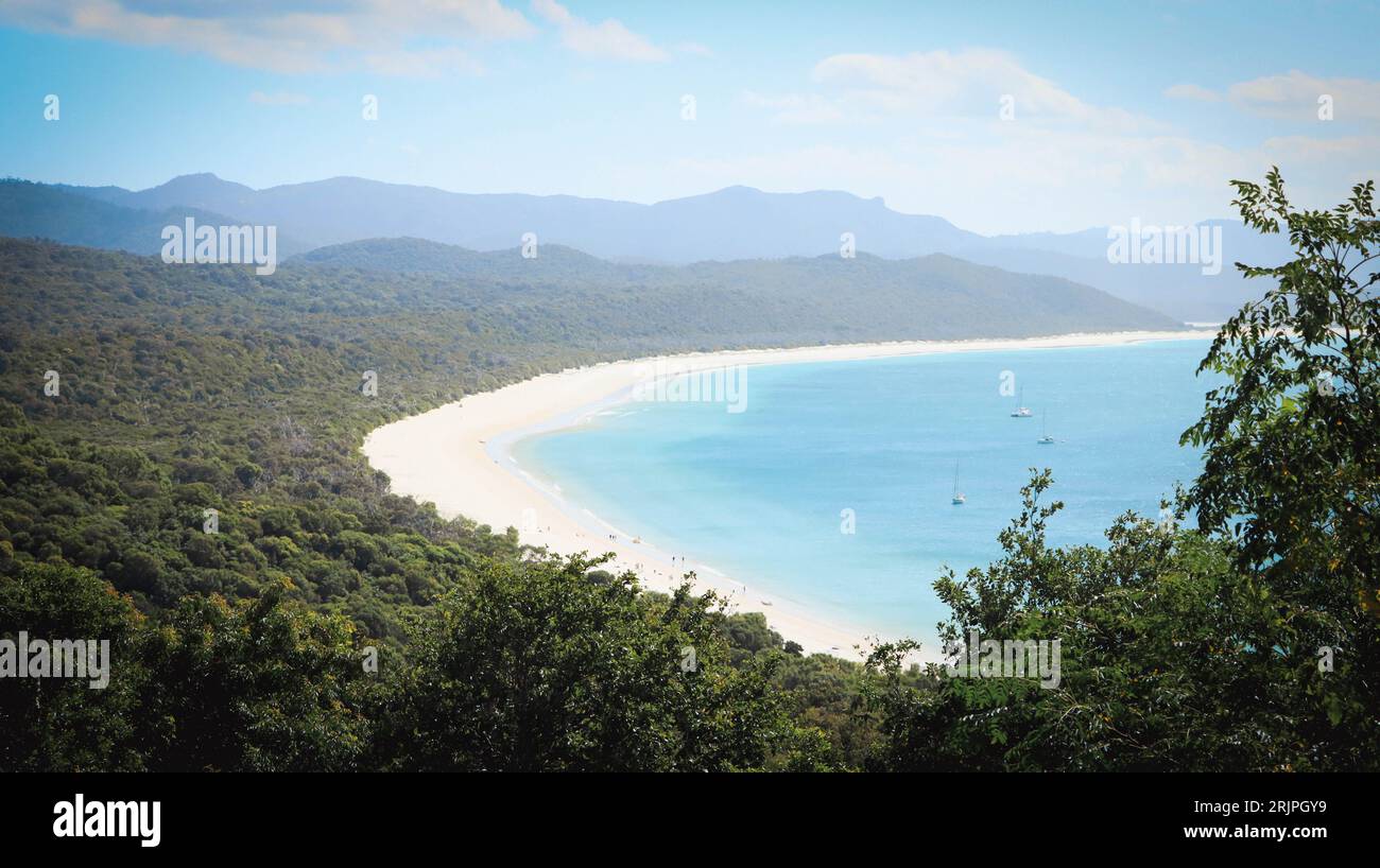 Una spiaggia incontaminata con acque cristalline e blu annidate in una lussureggiante area boschiva. Foto Stock