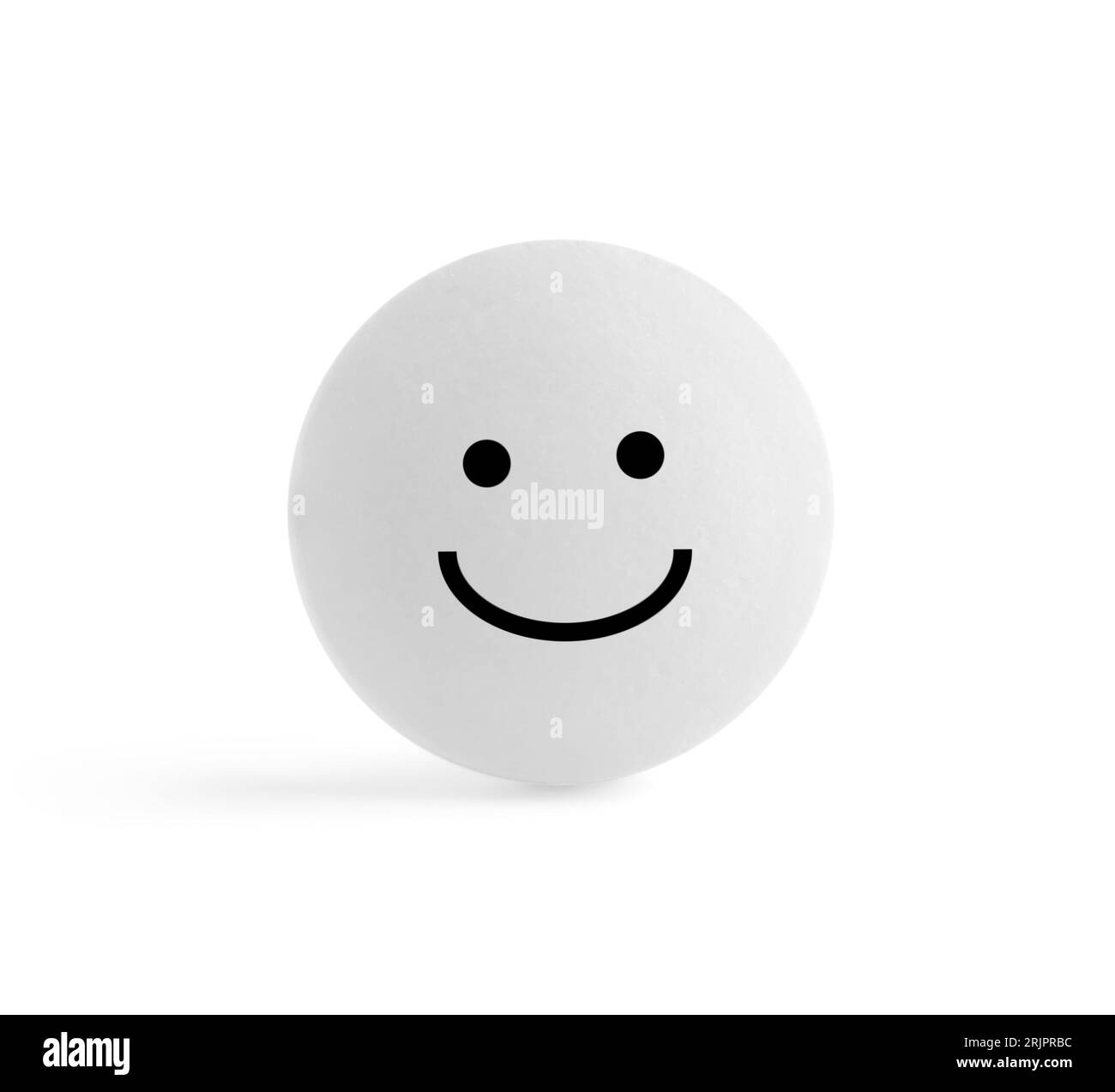 Una pillola rotonda con faccia sorridente su sfondo bianco Foto Stock
