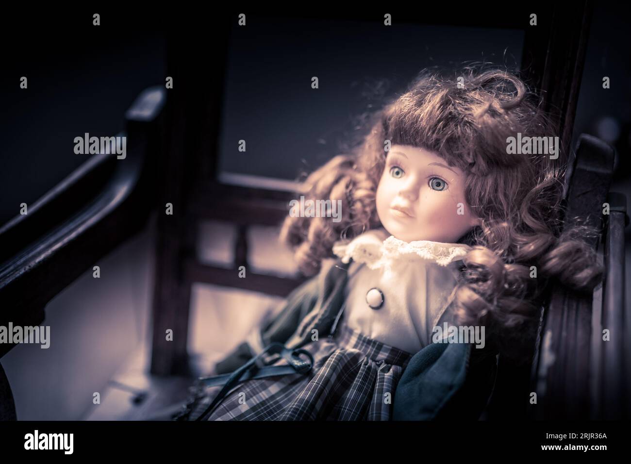 Bambola inquietante seduta su una sedia Foto Stock