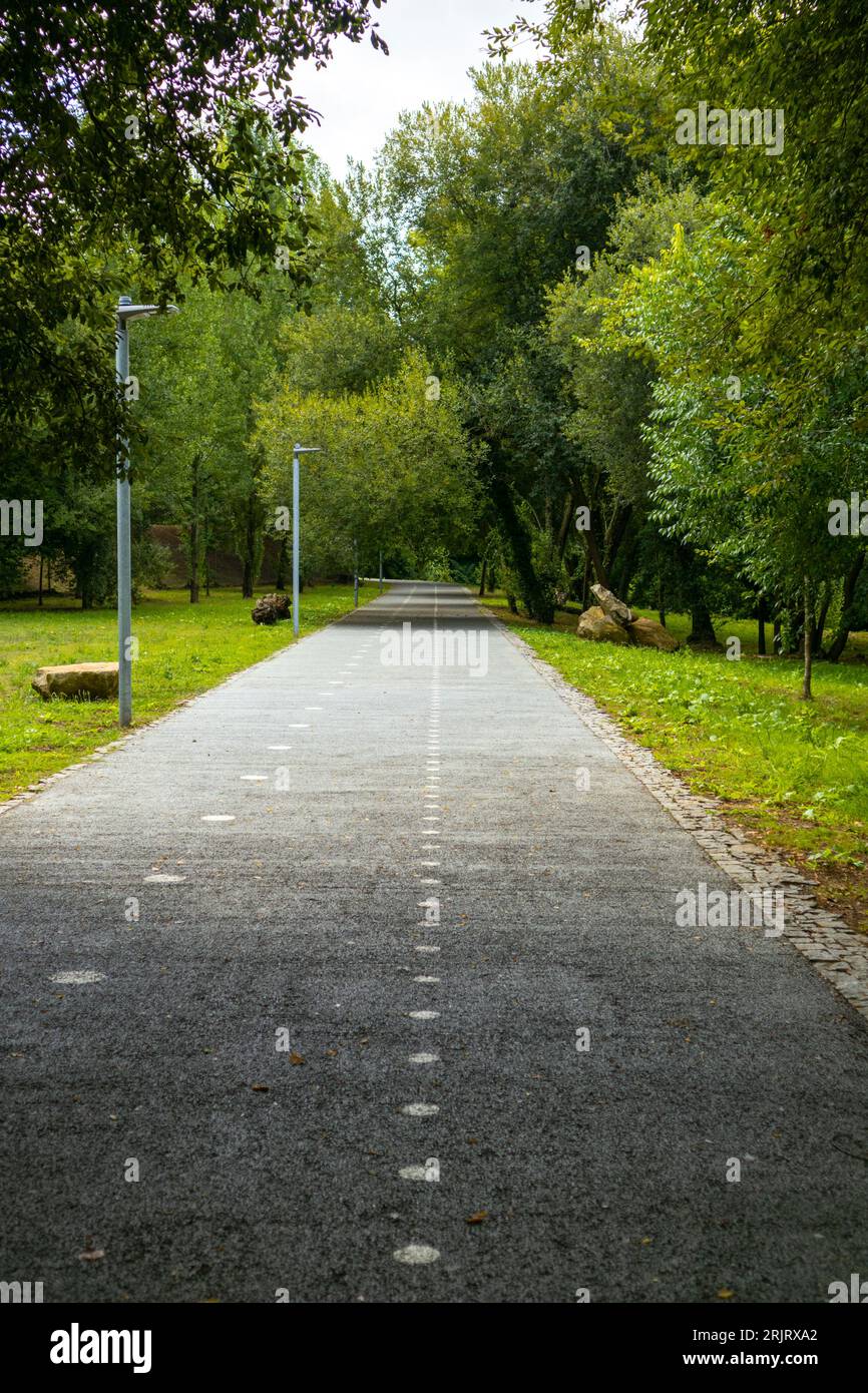 Una scena idilliaca di una strada tortuosa attraverso un lussureggiante parco verde, progettato per ciclisti e pedoni Foto Stock