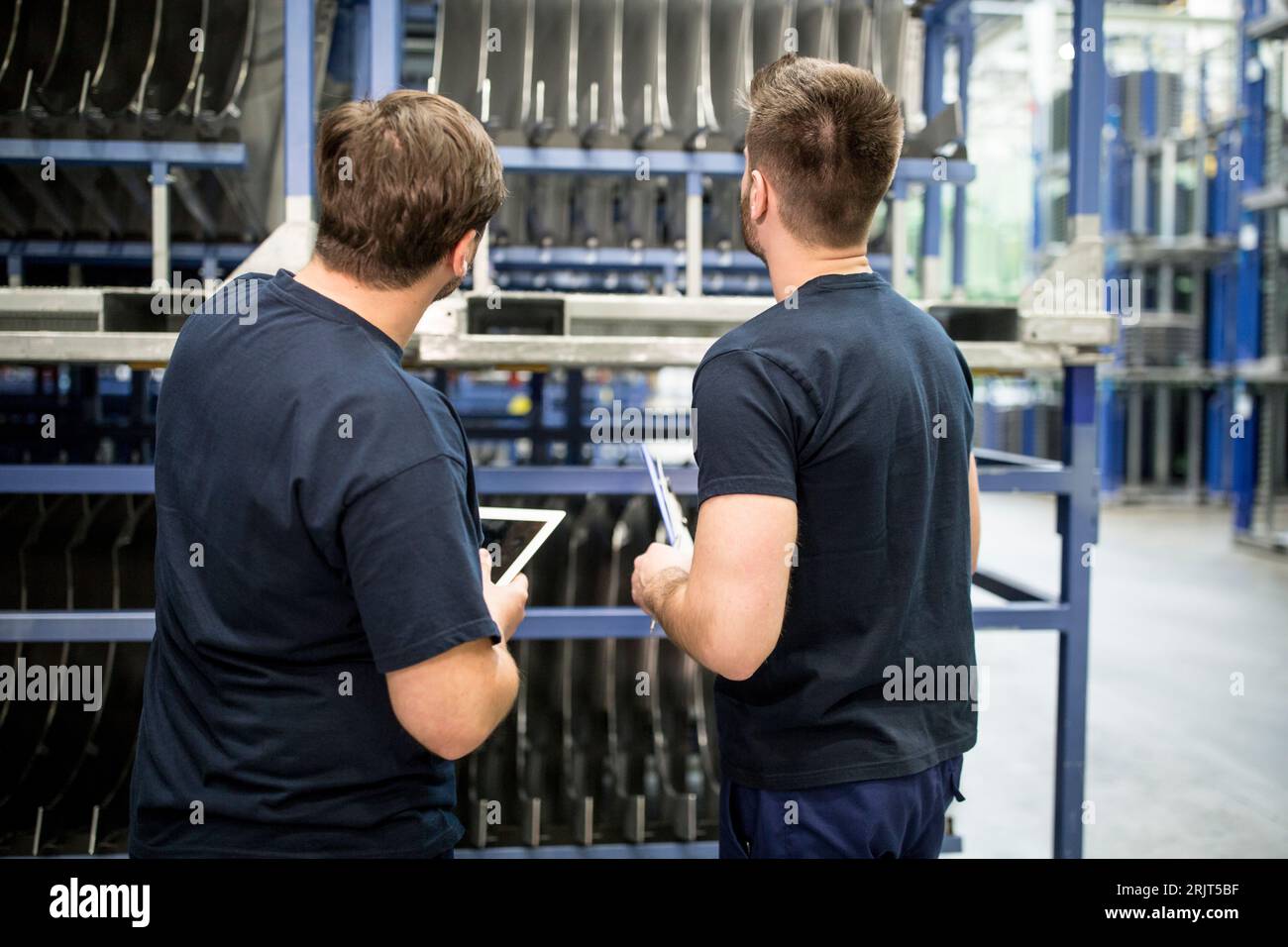 Due lavoratori con appunti e tablet in magazzino di fabbrica Foto Stock