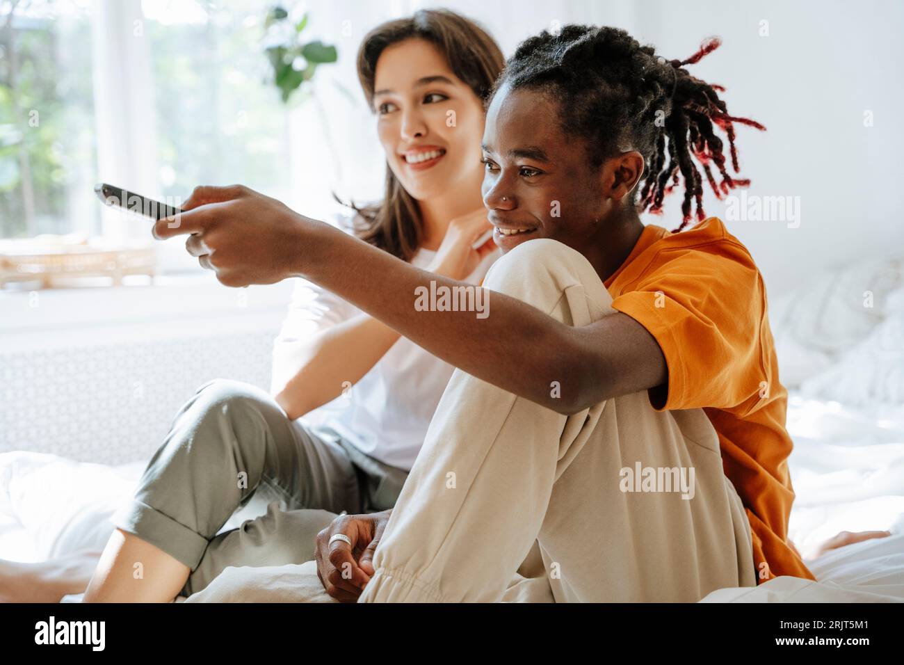 Coppia felice che guarda la TV seduta in camera da letto Foto Stock