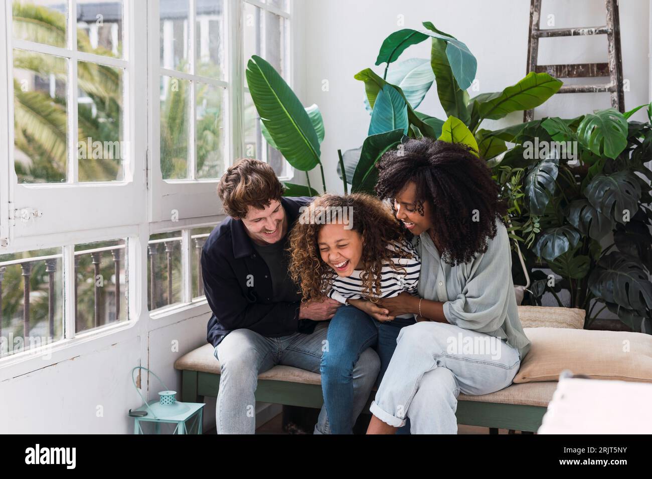 Una famiglia felice seduta nel giardino d'inverno che ride e si diverte Foto Stock