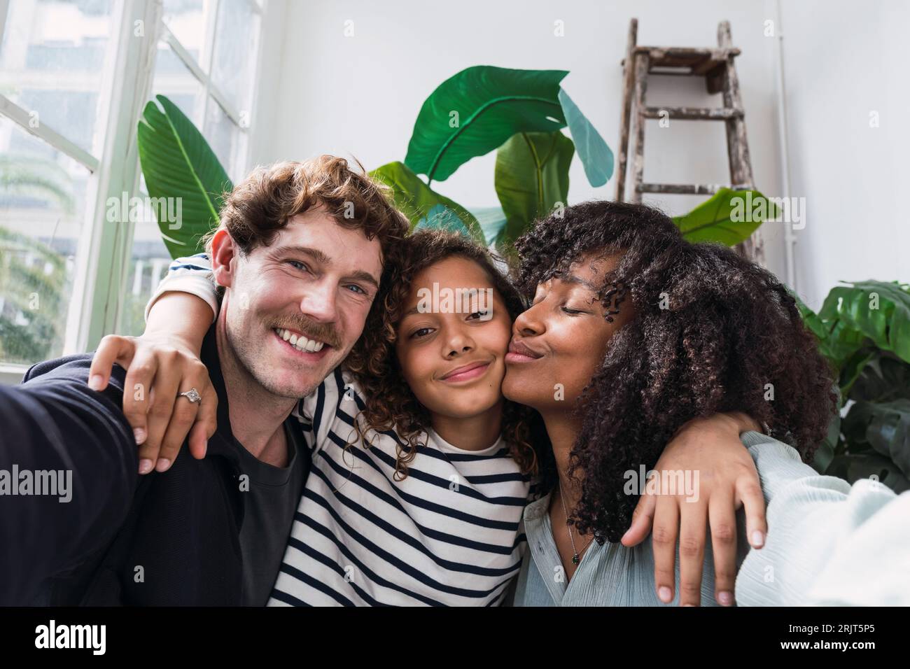 Una famiglia allegra cattura un momento insieme in un giardino d'inverno con un divertente selfie Foto Stock