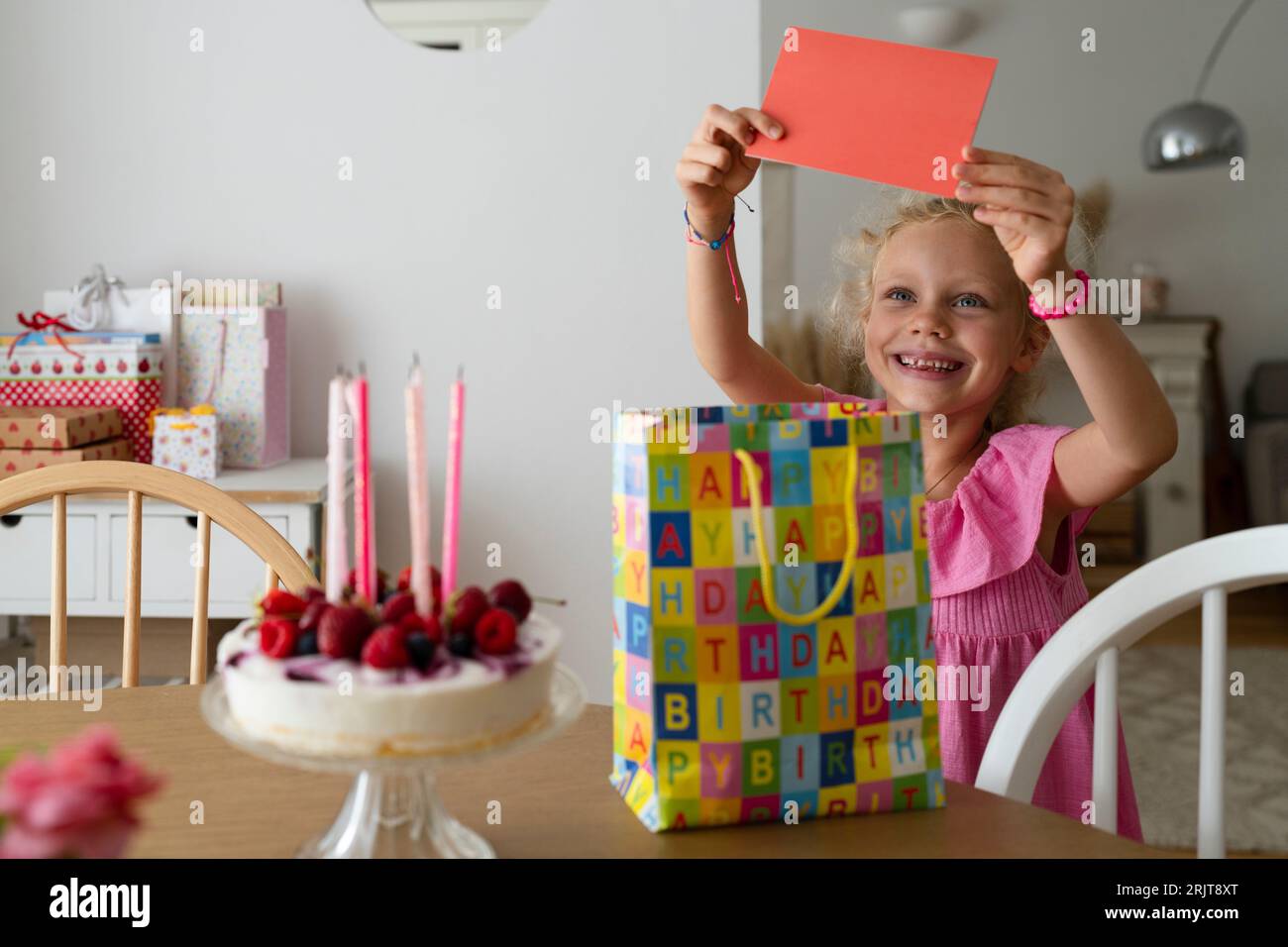 Ragazza sorridente con un biglietto di compleanno a casa Foto Stock